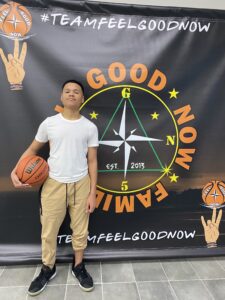 A man holding a basketball in front of a sign.